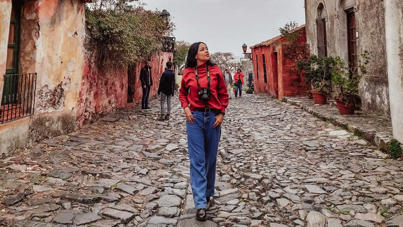 Uma mulher explorando a Calle de los Suspiros, uma atração imperdível para visitar em Colonia del Sacramento em um dia.