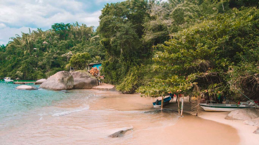 Praia de Paraty no Rio de Janeiro, com o mar azul fundindo com o verde da natureza.