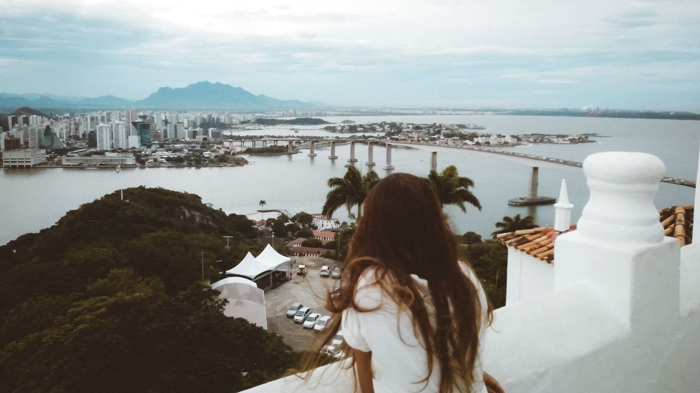 Mulher de cabelos longos apreciando a vista do Convento da Penha para vitória e para o Mestre Alvaro.