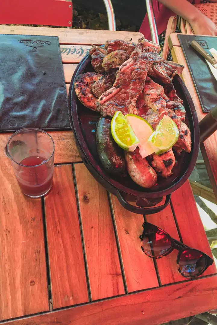 Foto da Parrilla Uruguaia, um churrasco com uma variedade de cortes de carne, acompanhado por um copo de sangria.