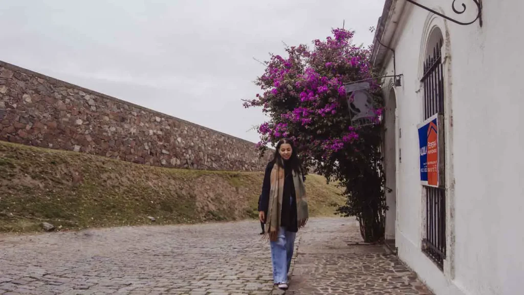 Mulher caminhando pelas ruas de pedras de Colonia del Sacramento em um dia nublado do inverno.