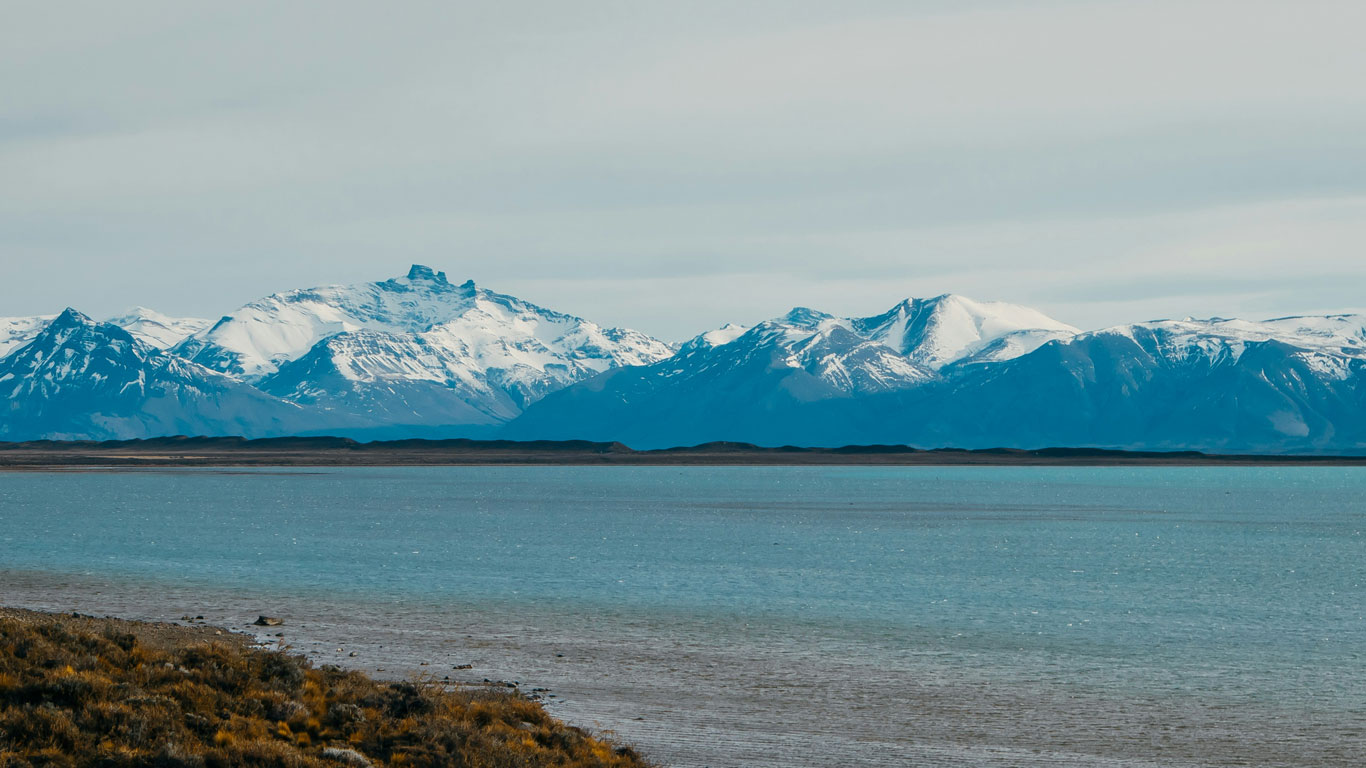 Vista do lago de El Calafate na Argentina, com águas azuis e as montanhas nevadas ao fundo.