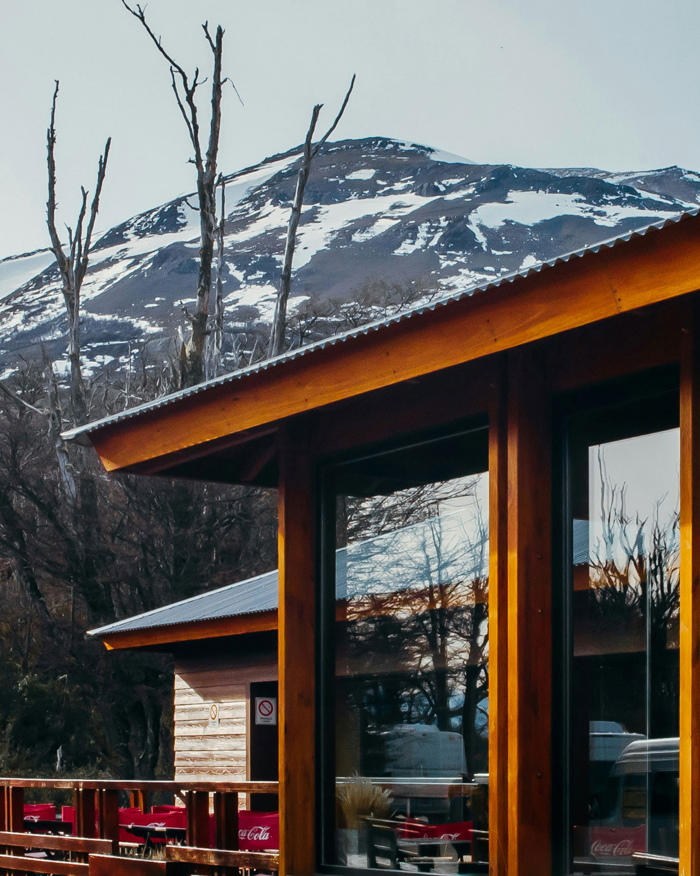 Casa no centro de El Calafate, com arquitetura de madeira e vidro, com montanha nevada ao fundo.