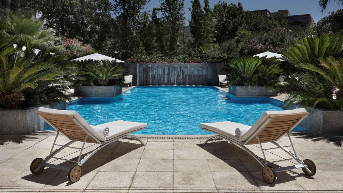 Piscina do Park Hyatt Hotel em Mendoza, com duas cadeiras vazias e vista para a natureza.