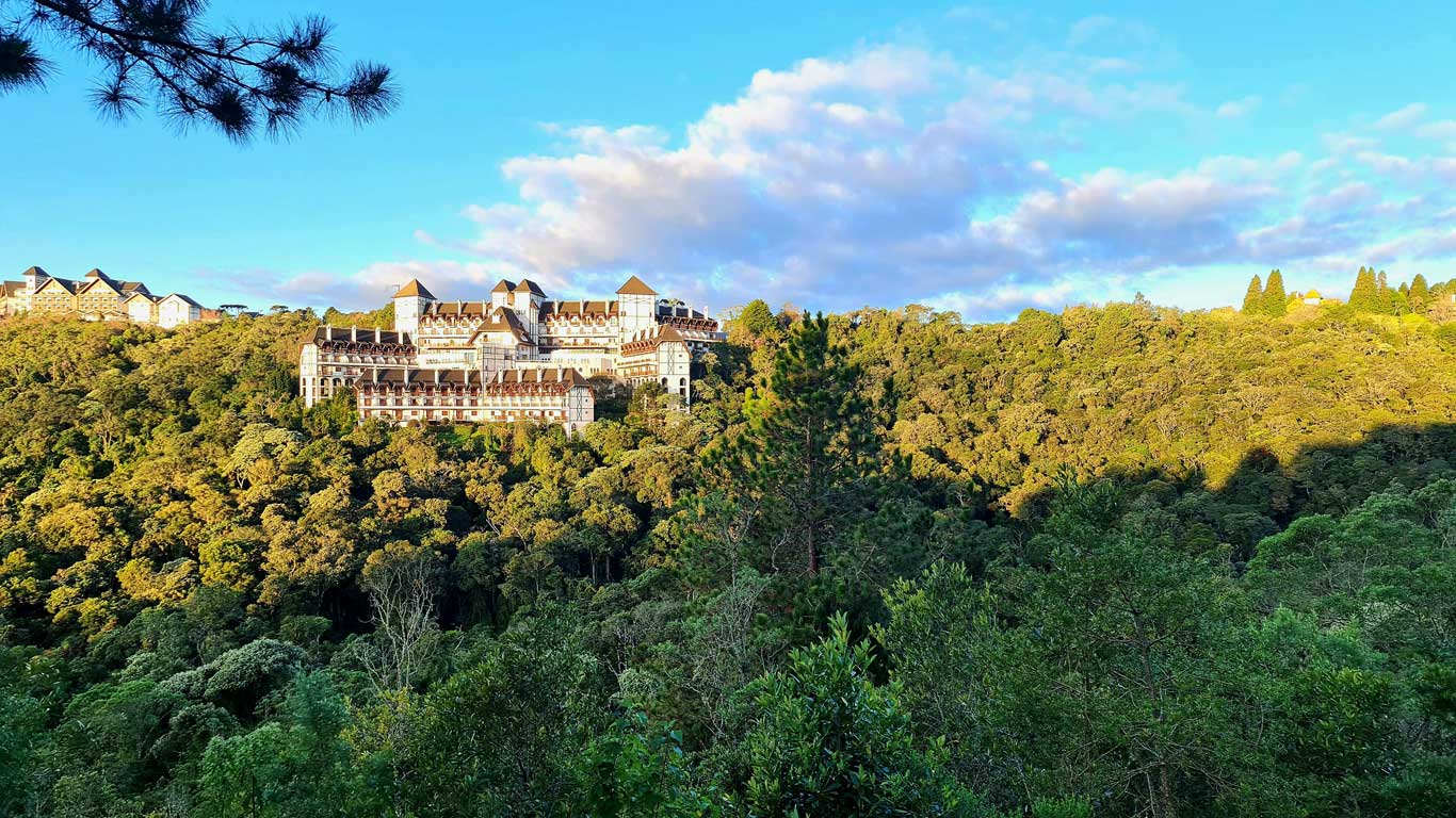 Vista de um hotel em Campos do Jordão, no mês de dezembro, com arquitetura Europeia, cercado pela vegetação.