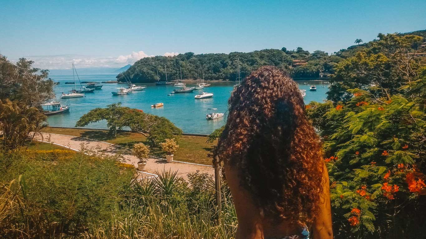 Uma mulher de cabelos ondulados admirando a Praia dos Ossos do alto, um dos melhores lugares para ficar em Búzios.