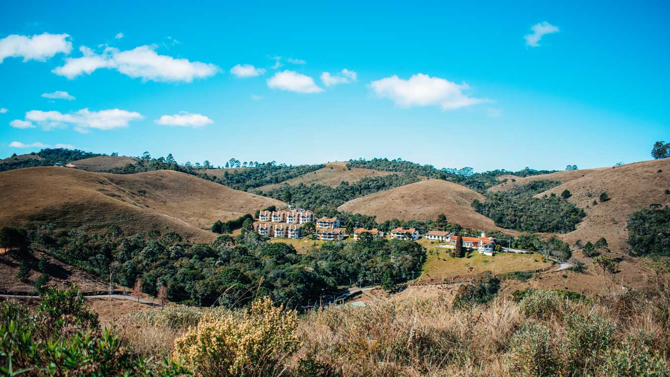 Imagem de paisagens de Campos do Jordão com construções coloniais em meio a natureza.