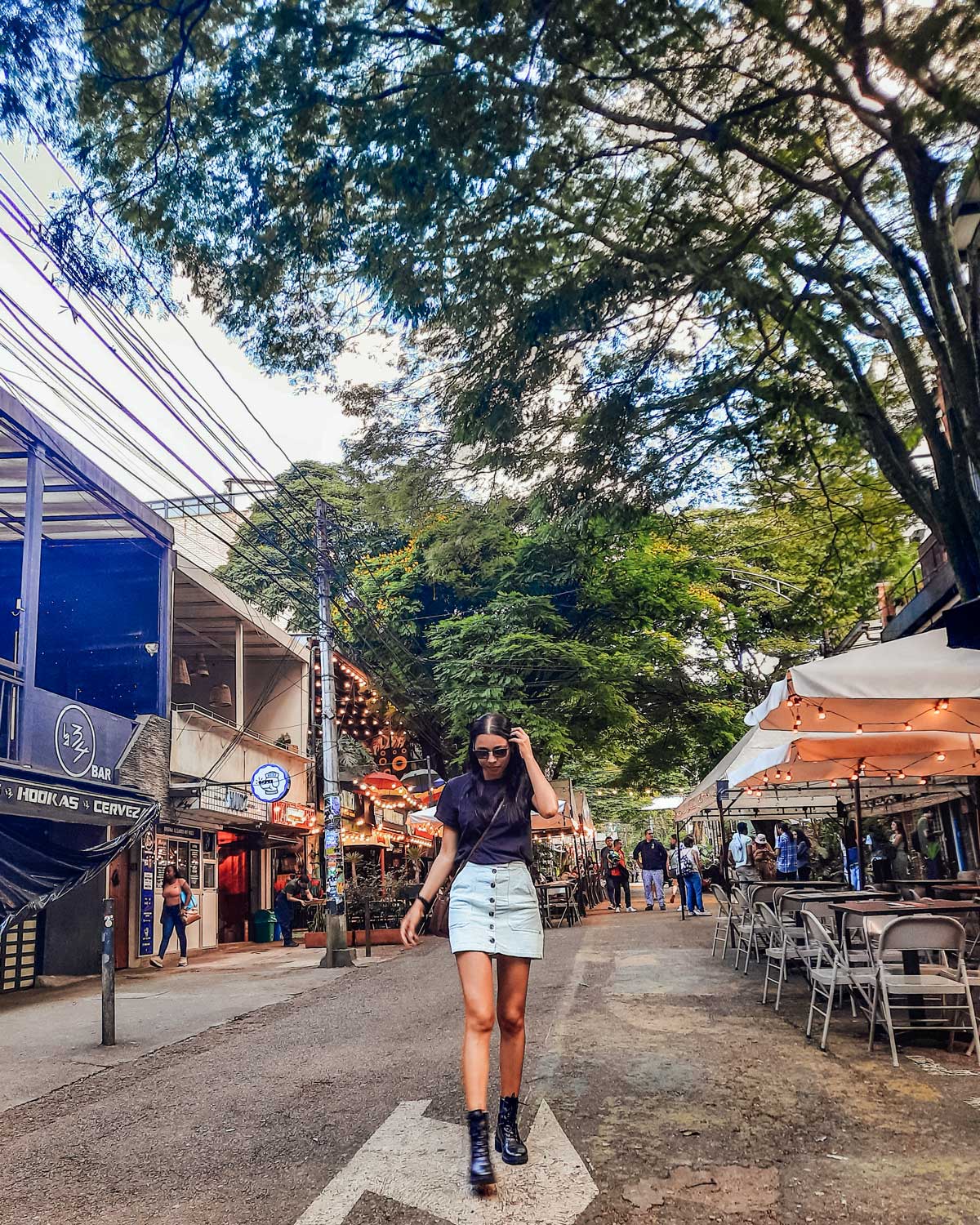 Mulher com sai jeans e blusa preta caminhando pela rua Provenza en El Poblado, o melhor bairro onde ficar em Medellín.