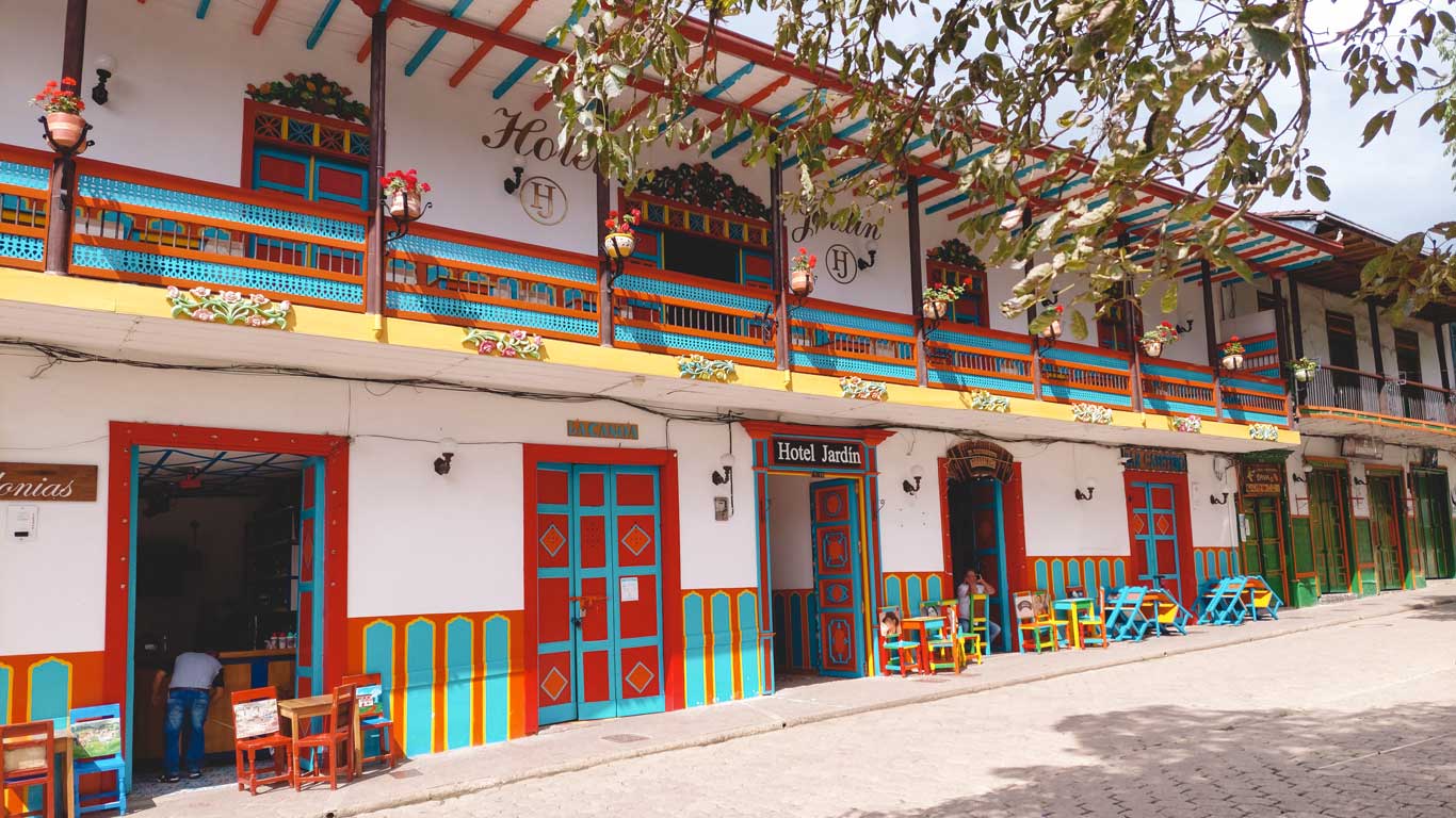 Hotel Jardín, um hotel de dois andares, com portas coloridas, localizado em frente a praça.