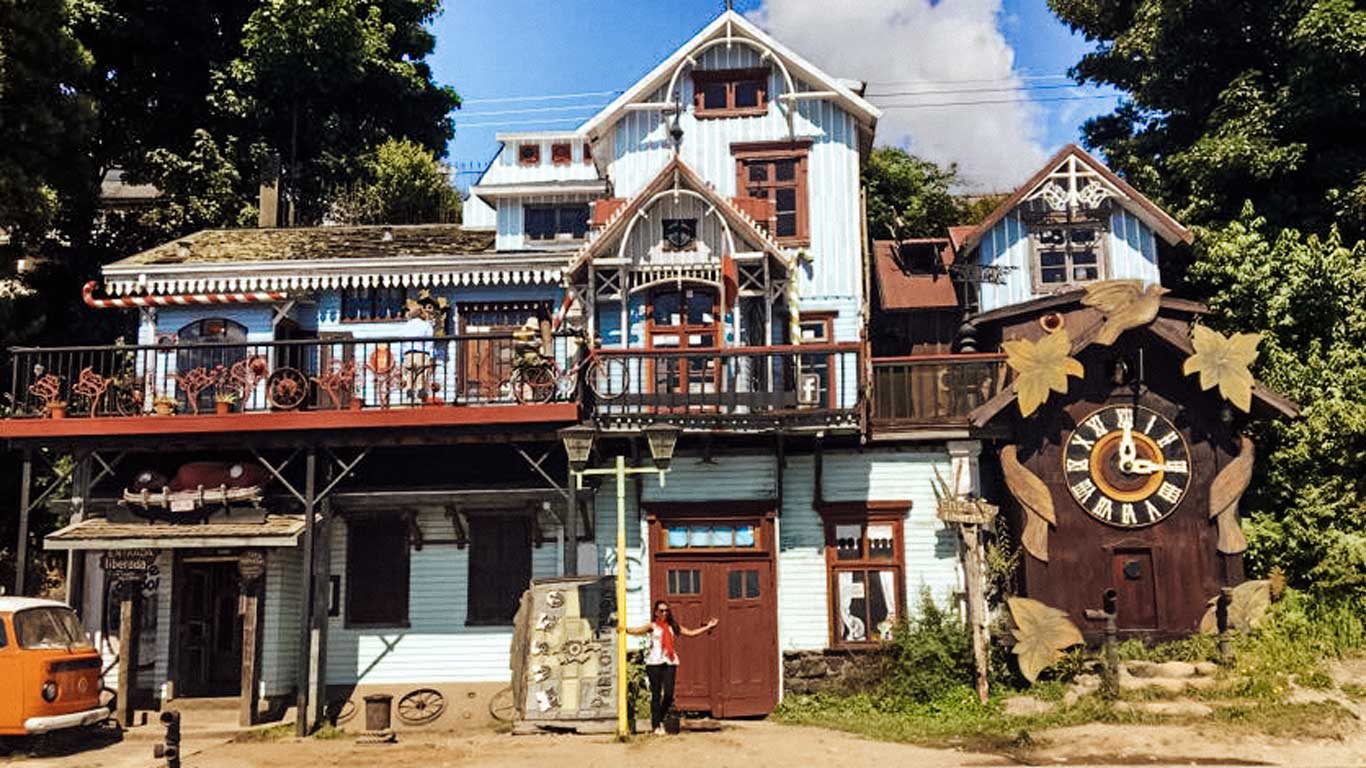 Fachada pitoresca do Museu Pablo Fierro, um museu em estilo rústico com detalhes em madeira, varandas e adornos antigos. Um relógio grande decora o exterior, realçando o charme do lugar.