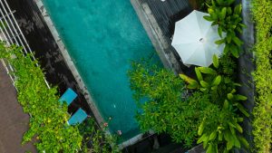 Vista aérea de uma piscina privativa com cadeiras, guarda-sol e plantas no seu entorno.