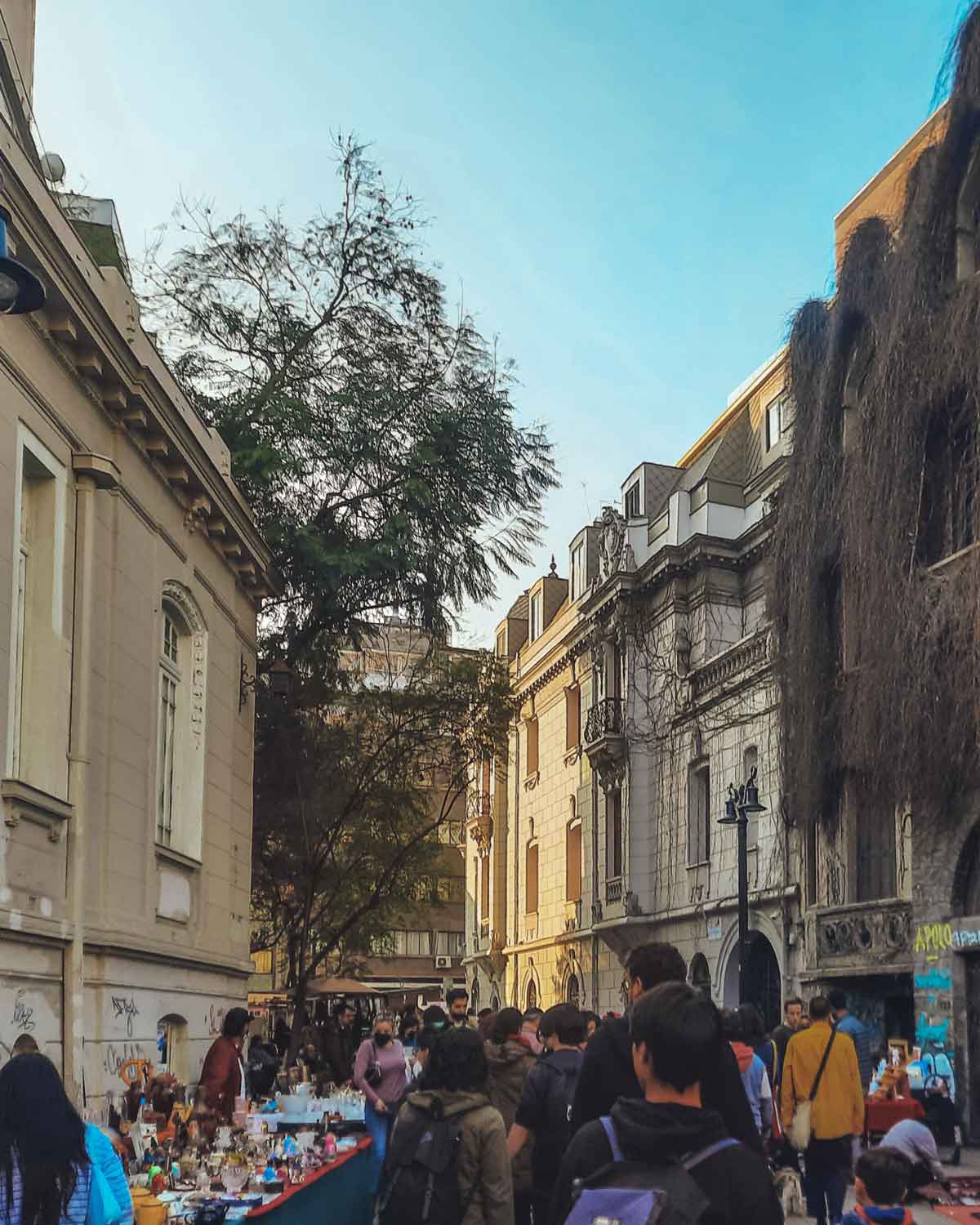 Uma movimentada feira de rua em Lastarria, o melhor lugar para ficar em Santiago do Chile, cercada por edifícios históricos e visitantes explorando as barracas.