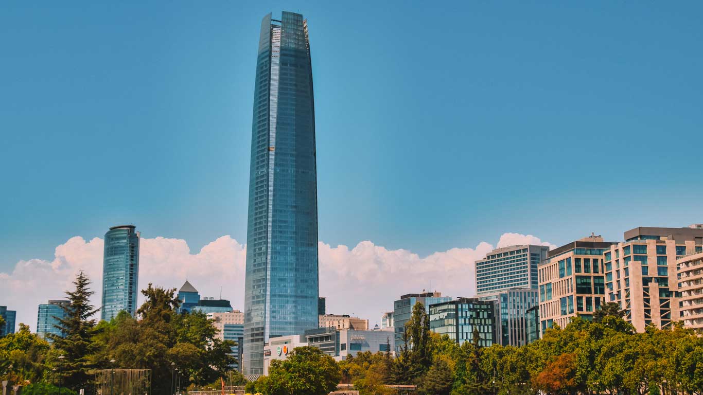 Vista do icônico edifício Costanera Center no bairro Providencia em Santiago, cercado por outros arranha-céus e vegetação. Providencia é um bairro seguro e moderno, ideal para se hospedar em Santiago.