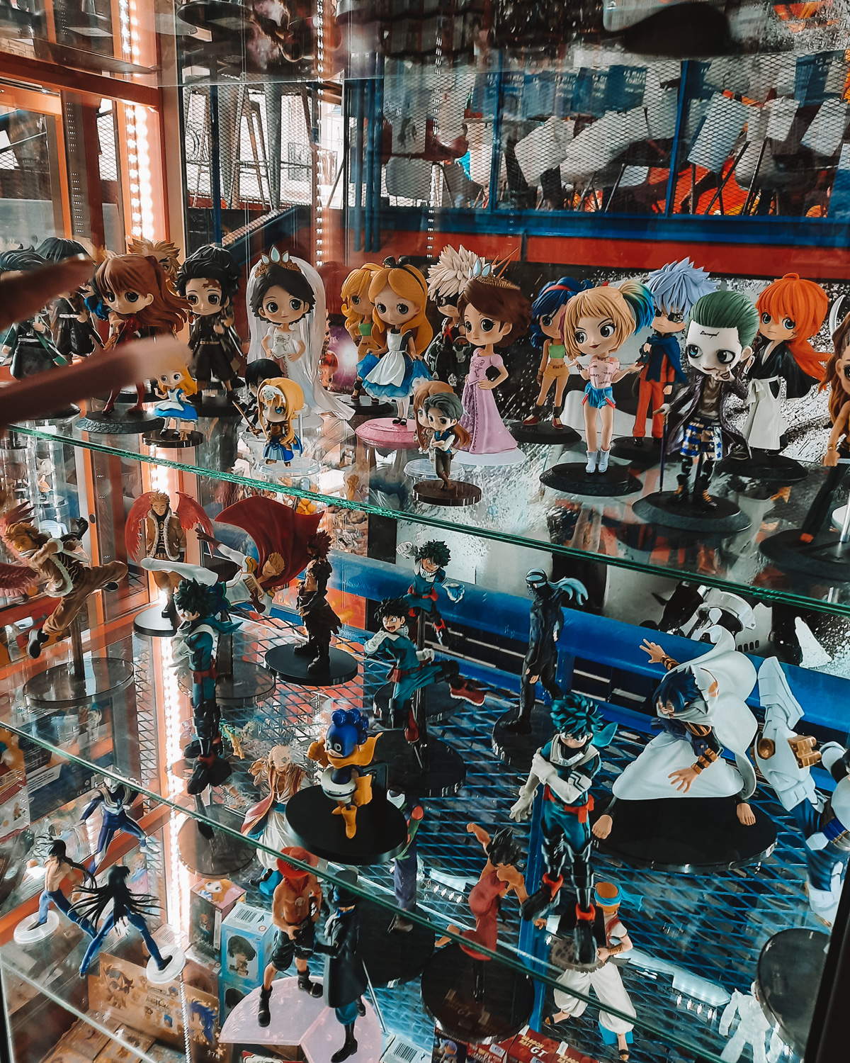 La-Revisteria-Buenos-Aires Estante de vidro da La Revisteria – Comics & Coffee, repleta de miniaturas de personagens de animes e desenhos, organizadas em fileiras iluminadas.