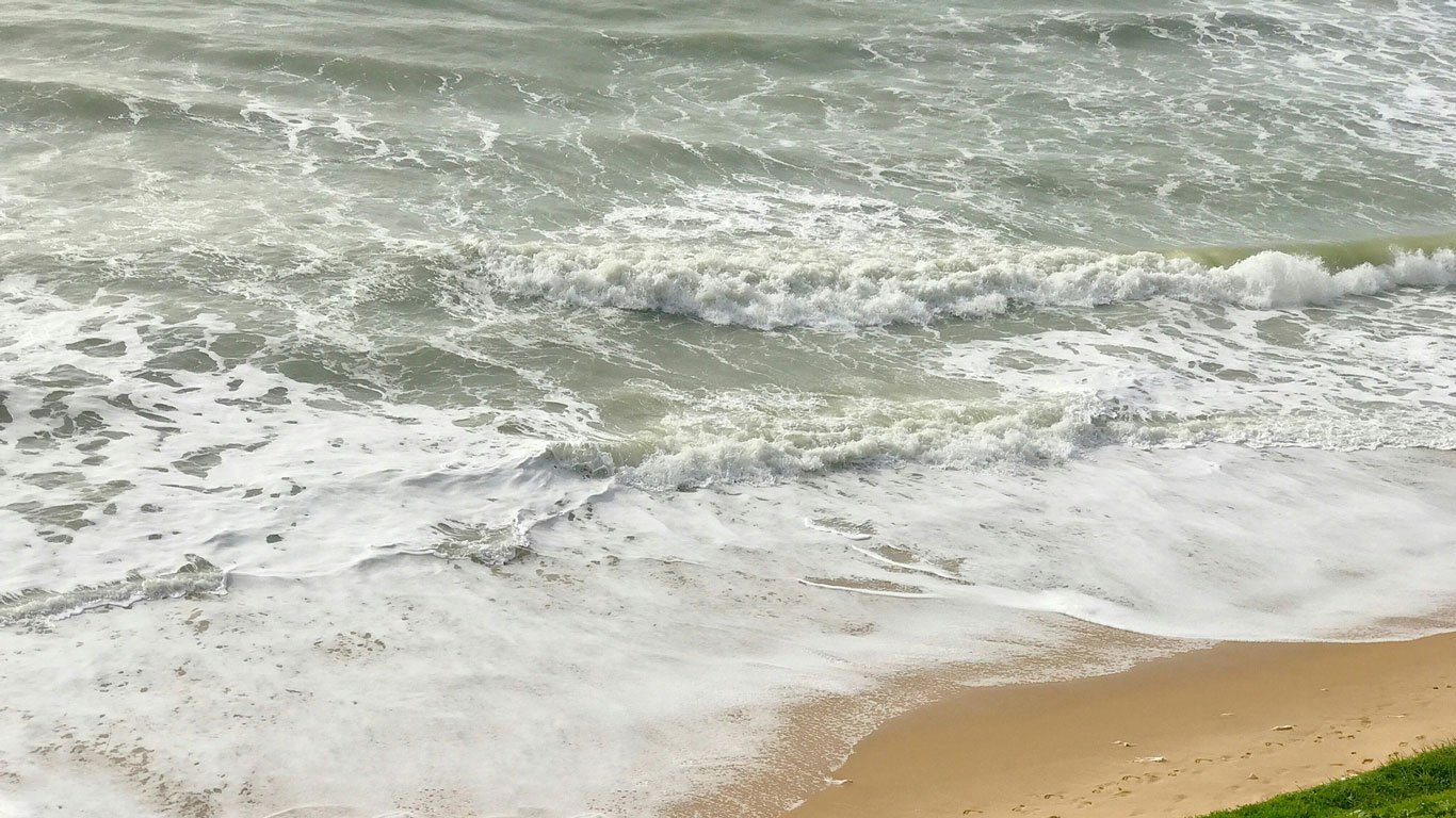 via-costeira-natal Mar agitado em Via Costeira, uma praia de areia dourada, com ondas espumosas quebrando na beira.
