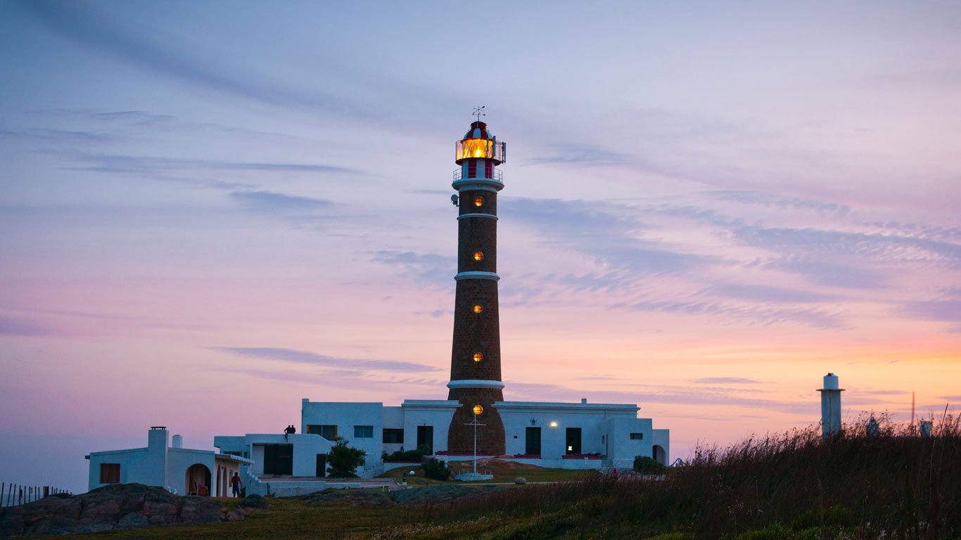 Farol de Cabo Polonio durante o entardecer, com o seu colorido de laranja e azul.
