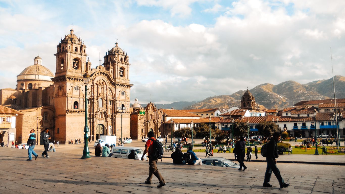 hoteis-em-machu-picchu Praça central de Cusco com a imponente Catedral e vista das montanhas ao fundo.