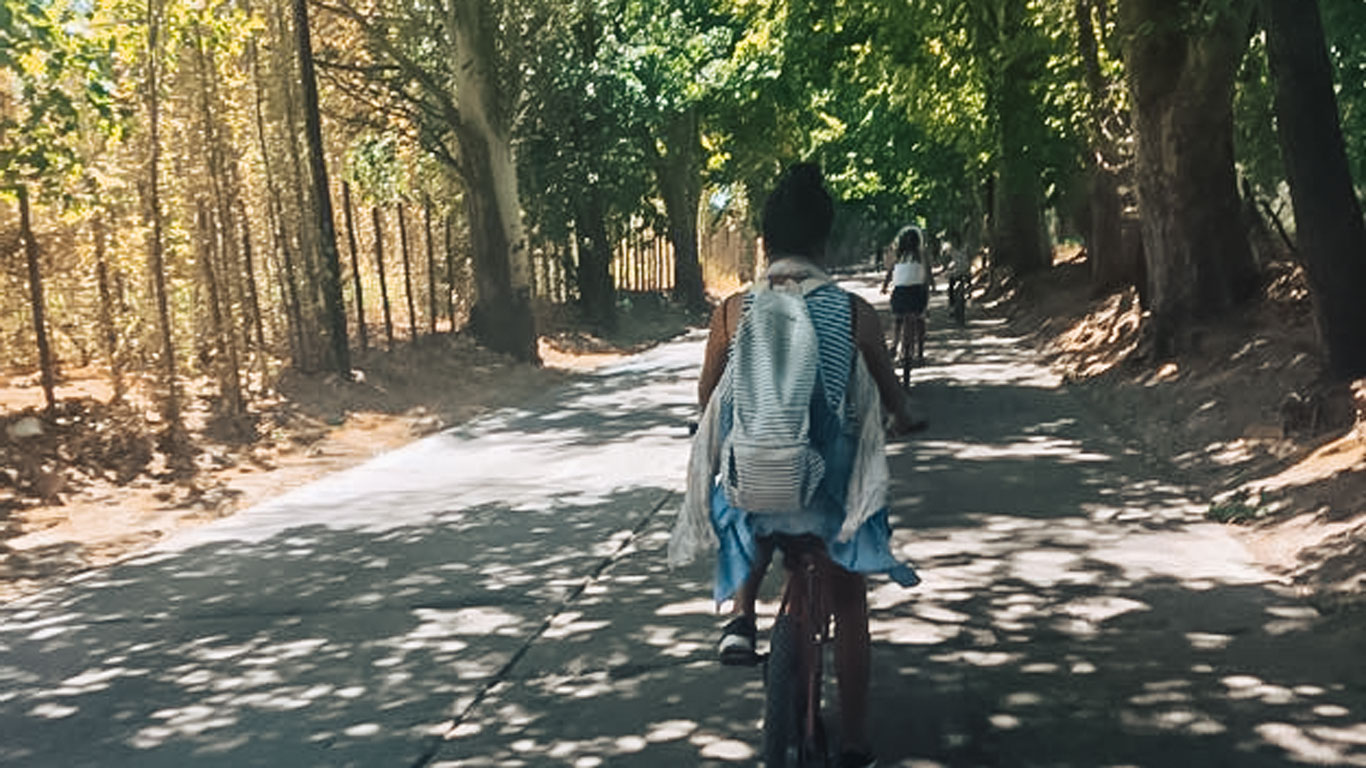 mendoza em outubro passeios Mulher andando de bicicleta em uma rua arborizada durante o passeio wine bike tour em Mendoza.